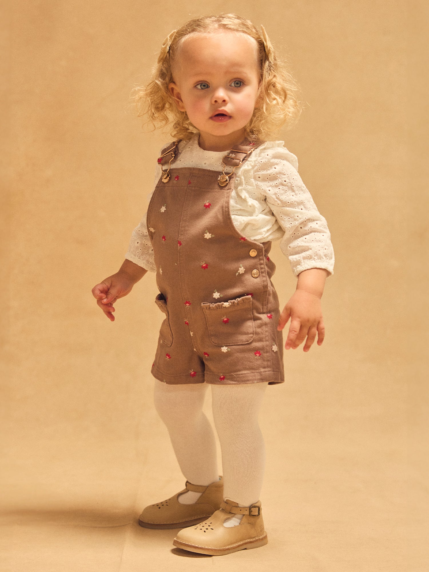 Kurze braune Latzhose mit Blumenmuster für Mädchen